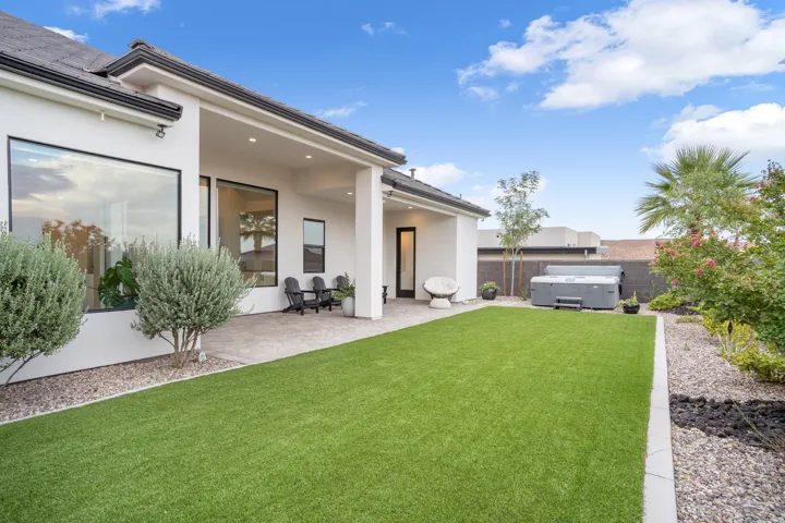 Expansive backyard featuring a synthetic lawn, paver patio, and low-maintenance landscaping