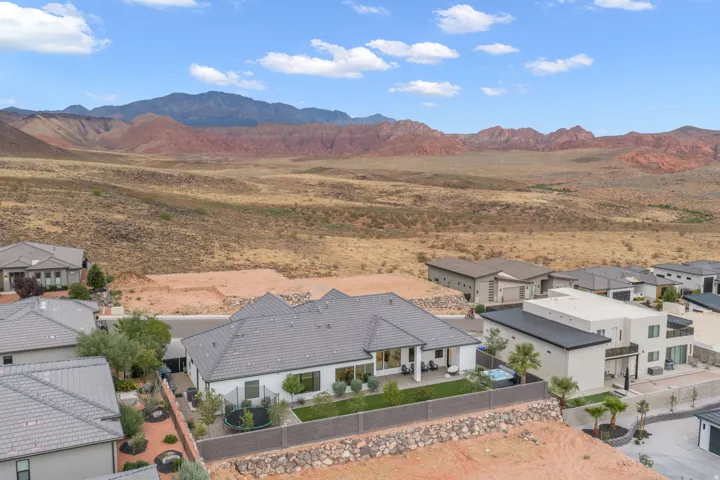 Modern residence featuring a gray tile roof, white stucco exterior, and a private rear patio with a hot tub