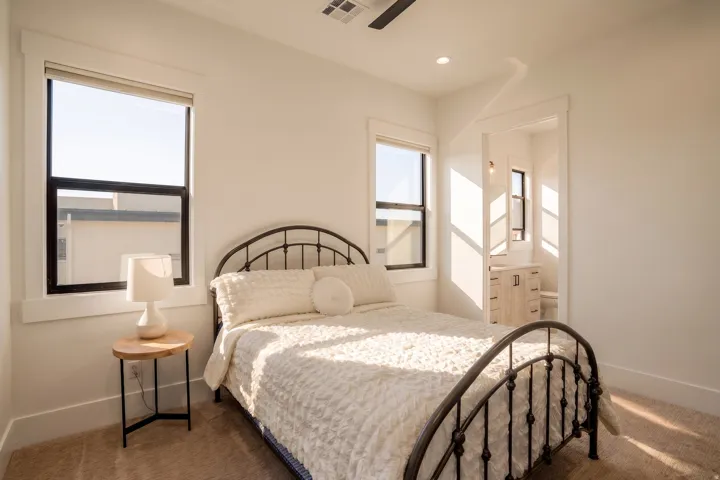 Bedroom with plush carpeting, two windows featuring dark frames and white trim, and a recessed ceiling light