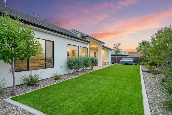 Expansive backyard featuring a lush green lawn, gravel landscaping, and mature trees