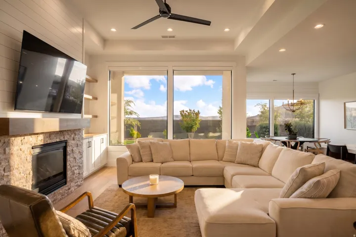 Living area featuring an integrated fireplace with a stone surround and wood mantle, shiplap accent wall, built-in cabinetry, and wood-finish flooring