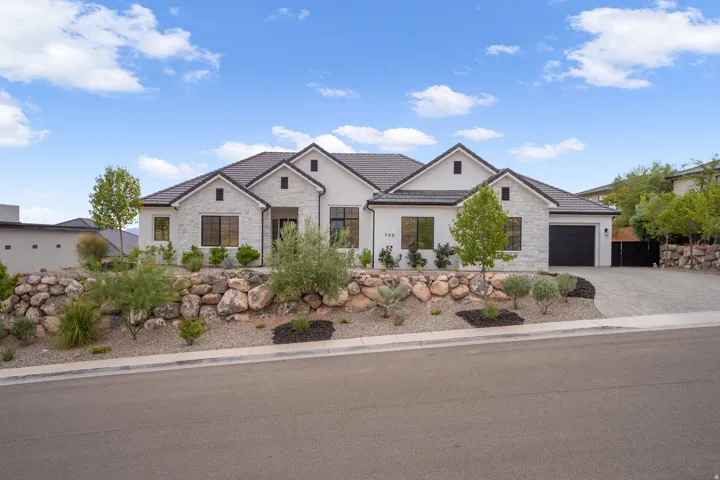Modern residence featuring a light-colored stone and stucco exterior, dark roof tiles, and black-framed windows