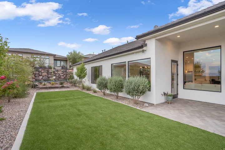 Private backyard featuring artificial turf, a paver patio, and mature landscaping