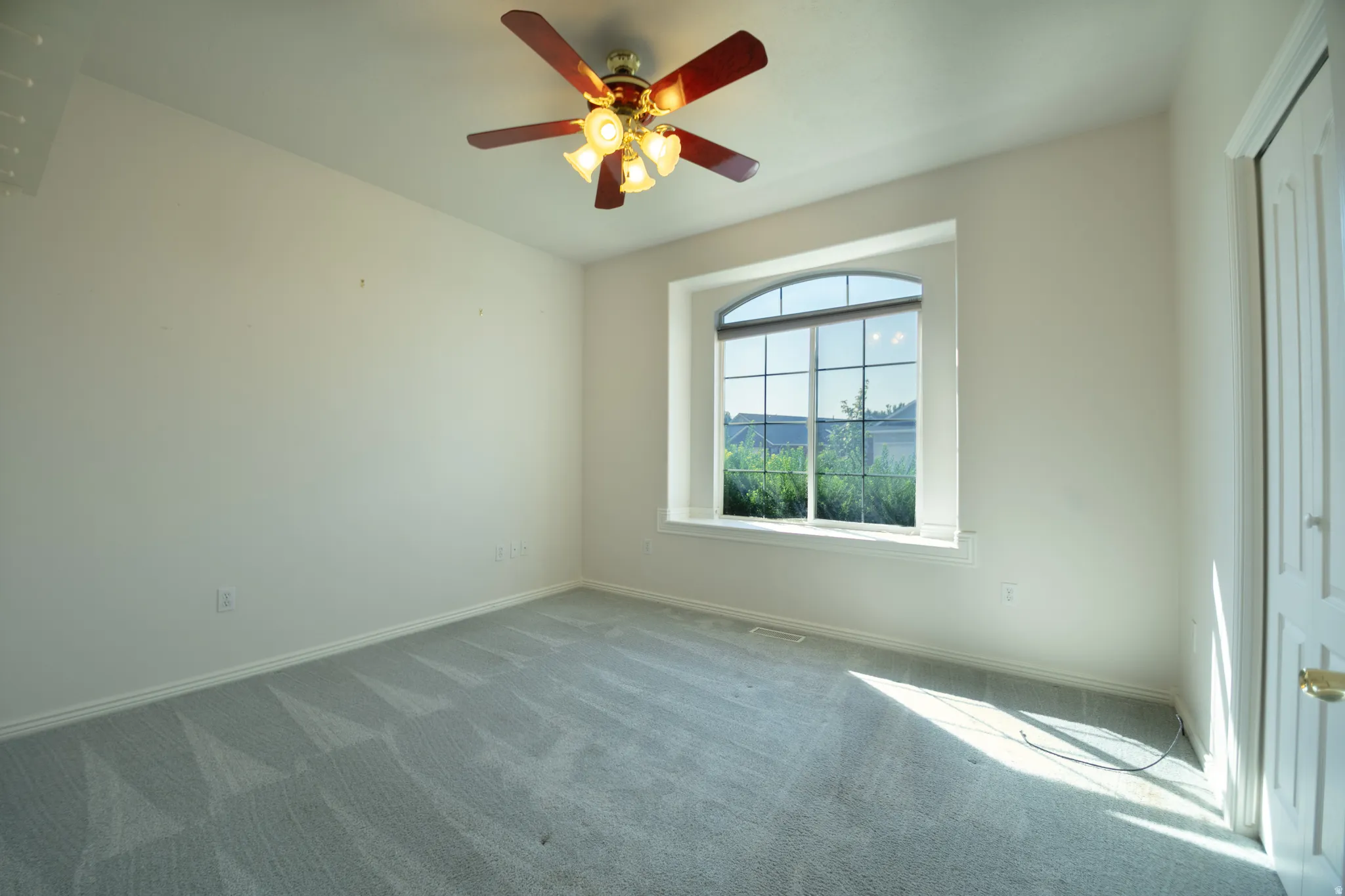 Arched window, ceiling fan, and light-toned wall finishes