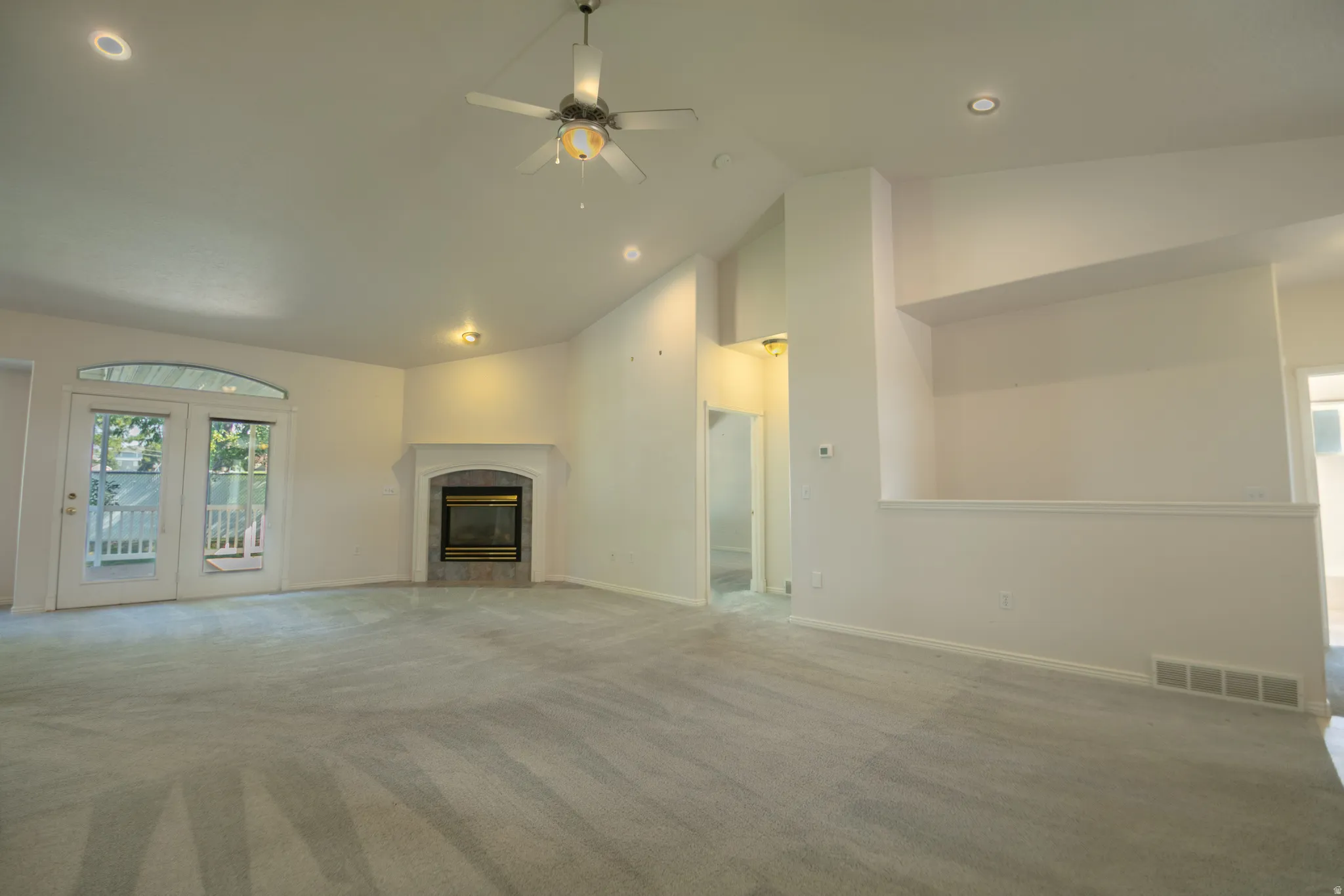 Vaulted ceiling, ceiling fan, recessed lighting, fireplace with stone surround, double french doors