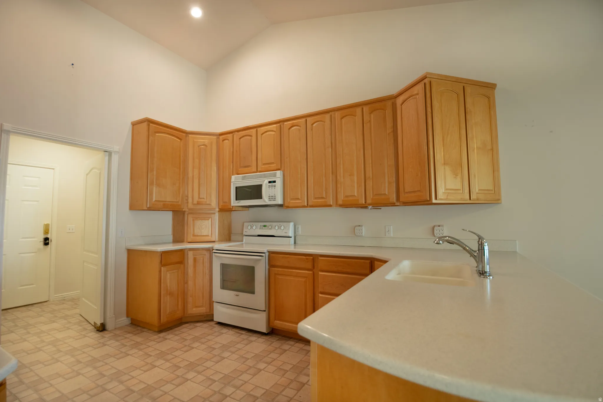 Kitchen featuring light wood cabinetry, light-toned countertops, integrated sink, and tile flooring