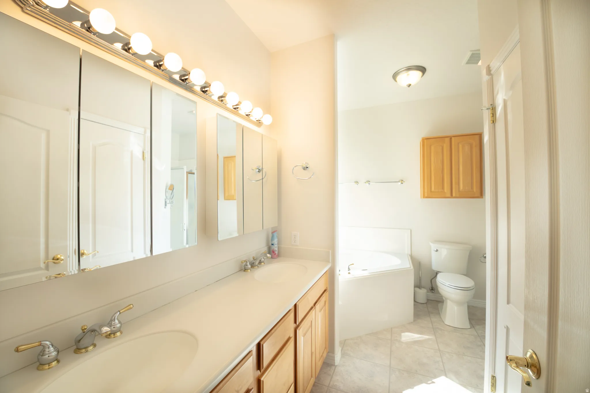 Dual vanity with ample countertop space, warm wood-finish cabinetry, and individual sinks