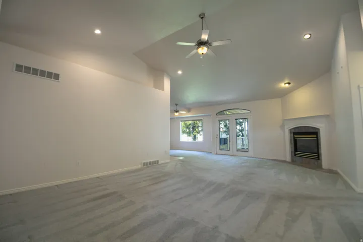 Vaulted ceilings with recessed lighting, ceiling fan, fireplace with mantel, and French doors