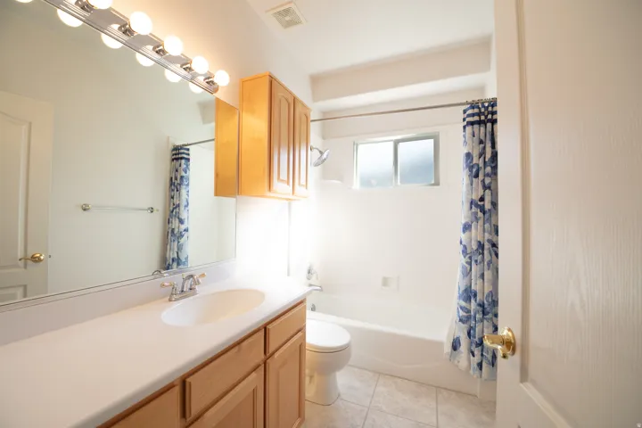 Bathroom featuring a single vanity with light wood cabinetry, a white countertop, and a large wall-mounted mirror