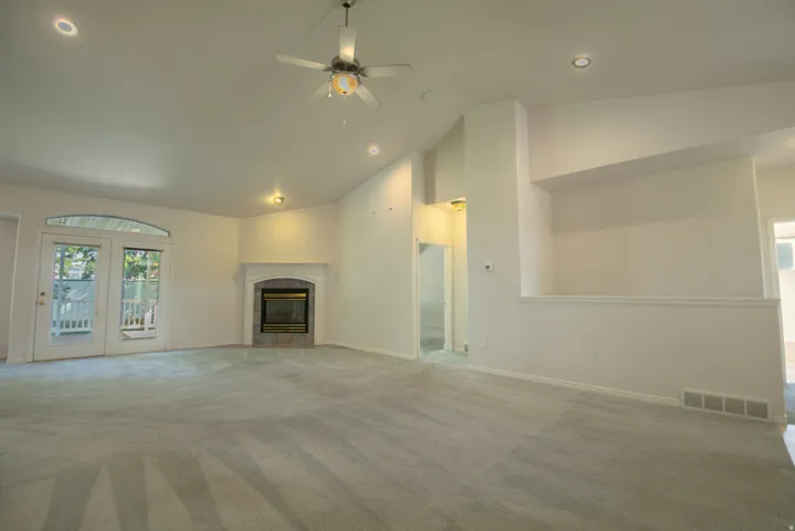 Vaulted ceiling, ceiling fan, recessed lighting, fireplace with stone surround, double french doors