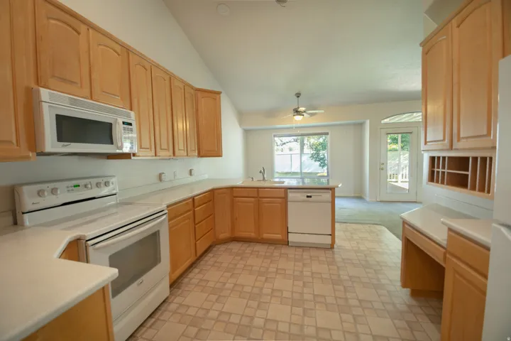 Kitchen featuring light wood cabinetry, white countertops, built-in microwave, and electric range