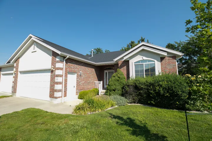 Brick facade with white trim, arched window, attached two-car garage, and established landscaping