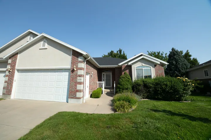 Brick and stucco exterior with an attached garage, covered entry, and a paved driveway