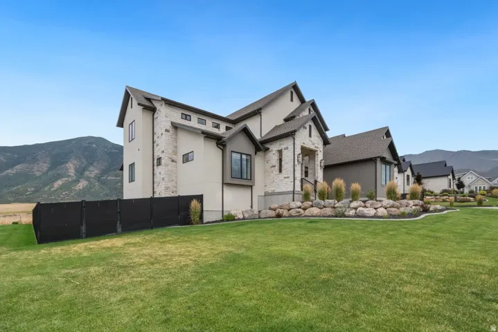 Contemporary exterior featuring stucco and stone accents, a multi-gabled roofline, multiple window styles, and a landscaped rock garden with ornamental grasses