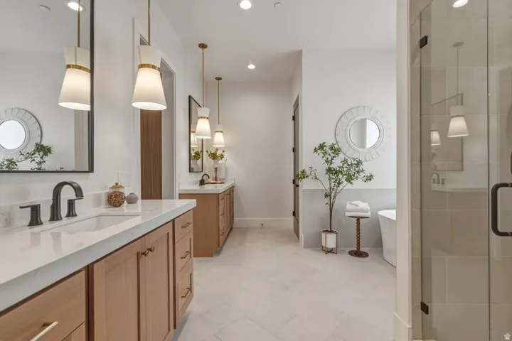 Spacious bathroom featuring twin vanity areas with light wood cabinetry, white countertops, and matte black fixtures