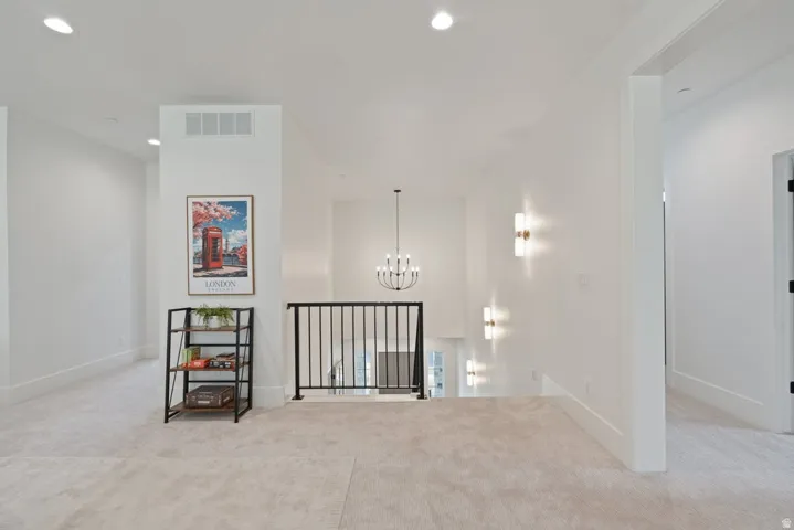 Carpeted second-story landing featuring a black metal railing overlooking the floor below