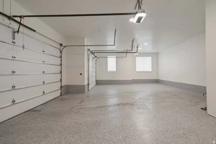 Spacious garage featuring a durable epoxy floor, white walls, and two overhead garage doors