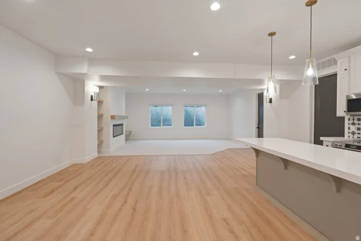 Open-concept living area featuring wood-finish flooring, recessed lighting, and a kitchen island with pendant lighting