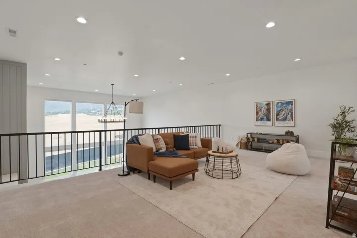 Expansive loft area featuring neutral carpeting, a black metal railing, and white walls