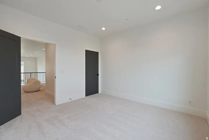 Carpeted room featuring recessed lighting, white walls, and dark interior doors