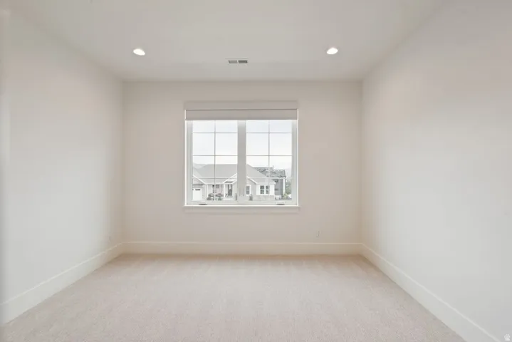 Bright interior space featuring a grid window, recessed lighting, and neutral tone carpeting