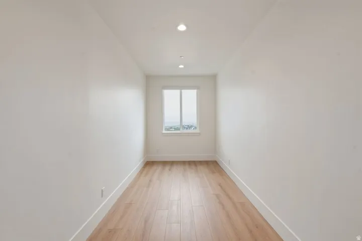 Recessed lighting illuminates this bright space featuring wood-finish flooring and a single window