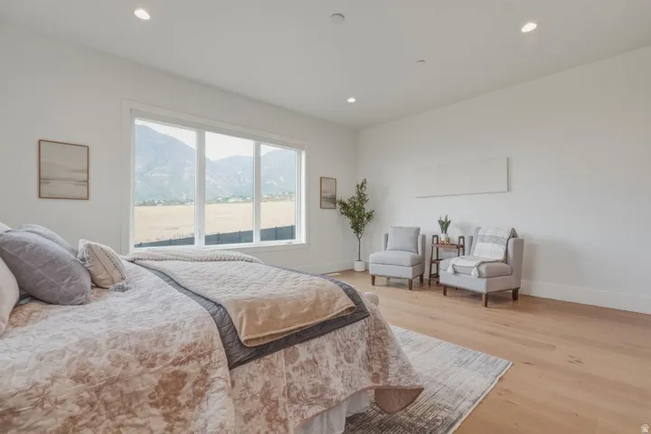 Spacious room featuring multiple large windows showcasing a mountain backdrop, light wood-finish flooring, recessed lighting, and crisp white walls