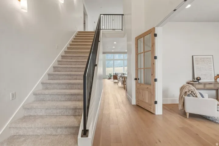 Carpeted staircase with black iron railing, complemented by light wood-finish flooring