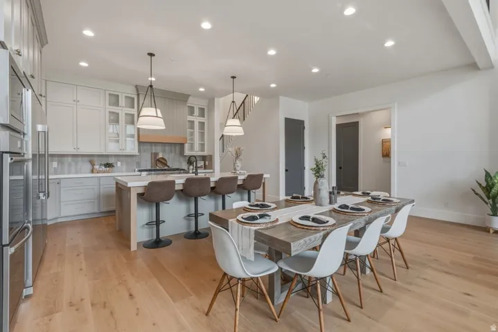 Open-concept kitchen and dining area featuring light wood-finish flooring, recessed lighting, and a kitchen island with pendant lighting