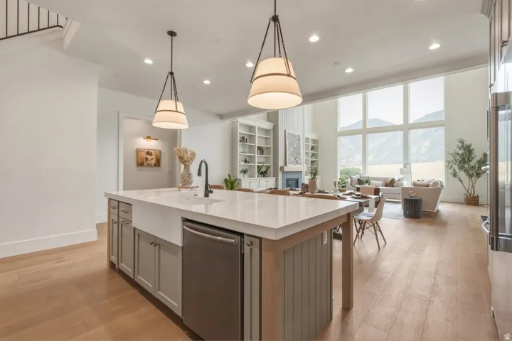 Modern kitchen island featuring a farmhouse sink, stainless steel dishwasher, and two pendant light fixtures