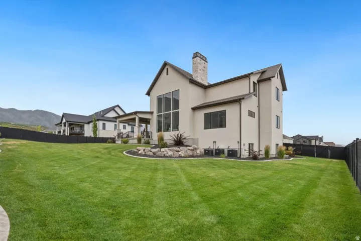 Expansive lawn area featuring a stone-clad chimney and a multi-level window arrangement