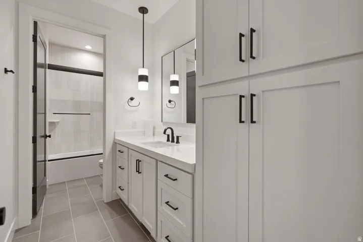 Bathroom vanity featuring white cabinetry, a light-colored countertop, and a rectangular undermount sink with a matte black faucet