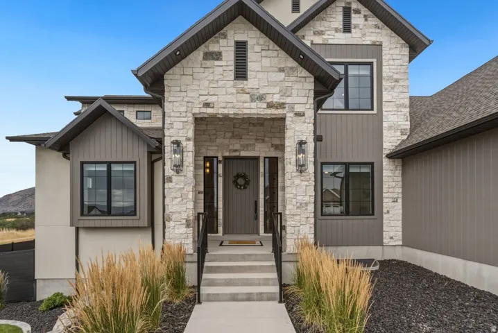 Stone facade entry with a dark wood-finish front door, flanked by vertical wall sconces