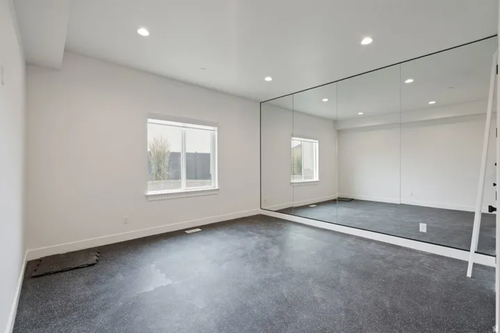 Spacious room featuring a full wall of mirrors, recessed lighting, and resilient flooring