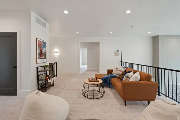 Spacious loft area featuring light-toned carpeting and recessed lighting