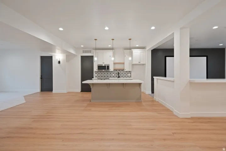 Open-concept living area featuring wood-finish flooring, recessed lighting, and a kitchen island with pendant lighting