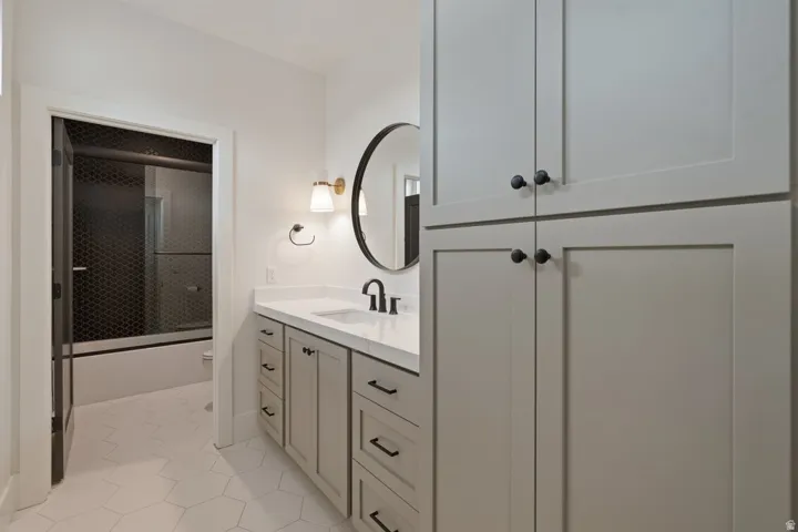 Bathroom featuring a light-toned vanity with a white countertop and black hardware