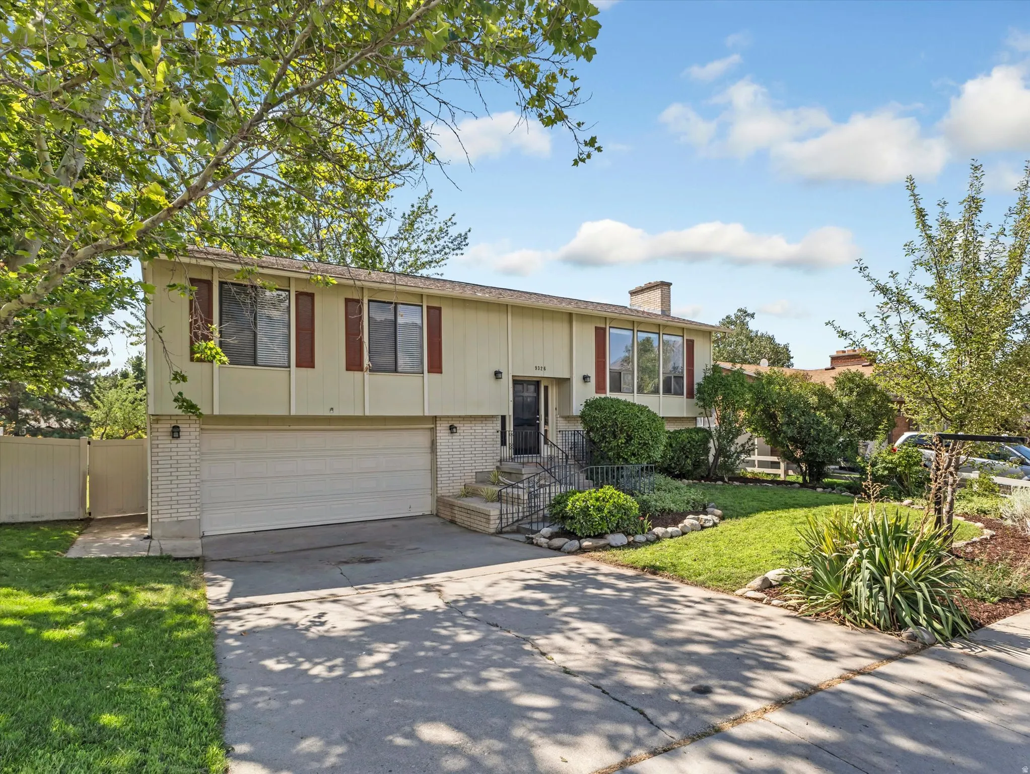 Split-level residence featuring a two-car garage, brick facade detailing, and a concrete driveway