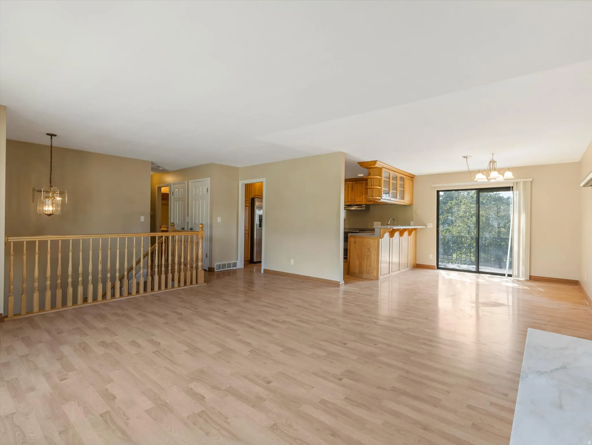 Open concept living space featuring wood-finish flooring, a kitchen area with wood cabinetry and built-in breakfast bar, and a sliding glass door