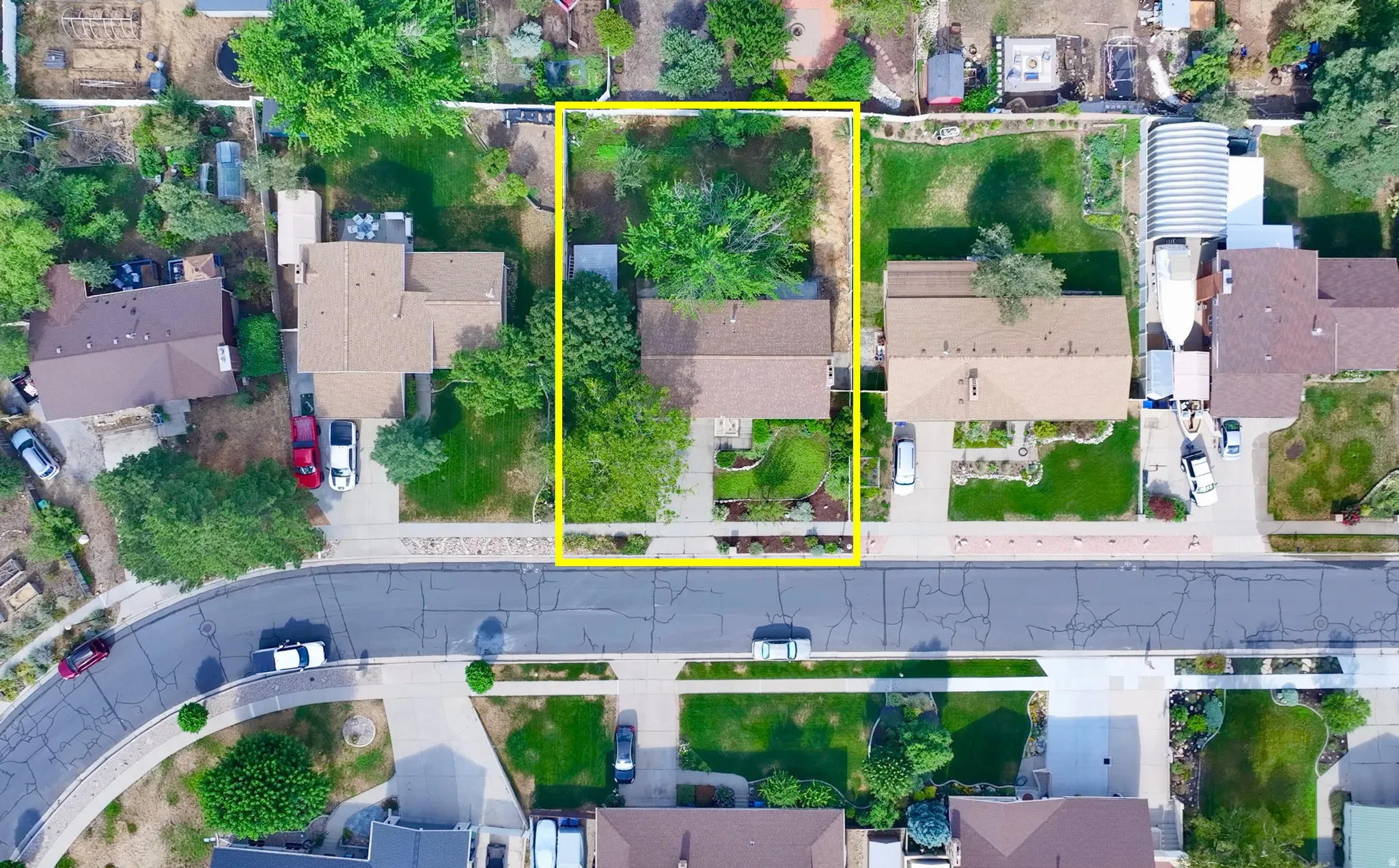Aerial perspective showcasing a residential property with a defined lot boundary, featuring mature trees and established landscaping