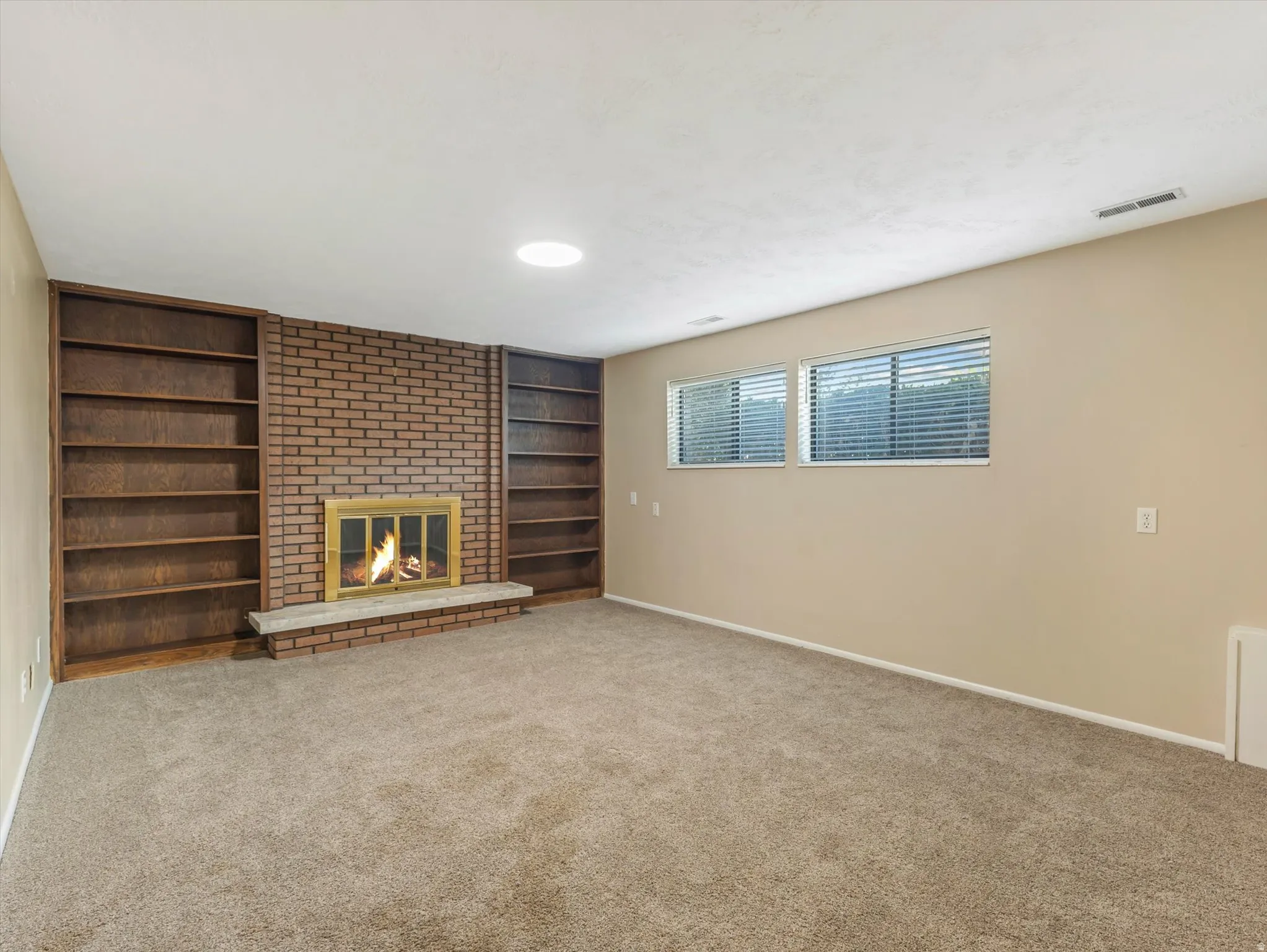 Brick fireplace featuring a stone hearth and brass-trimmed firebox