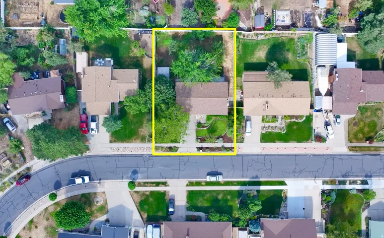 Aerial perspective showcasing a residential property with a defined lot boundary, featuring mature trees and established landscaping