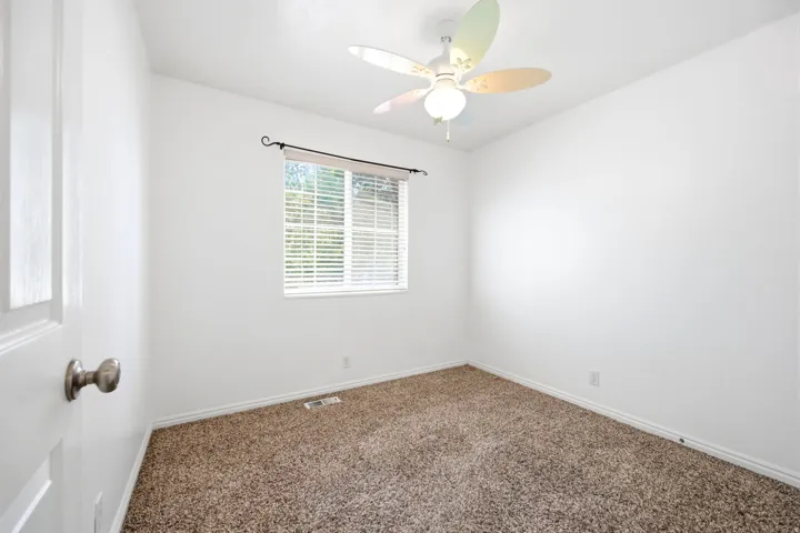 Room featuring light-colored walls, brown carpet flooring, and a window with blinds