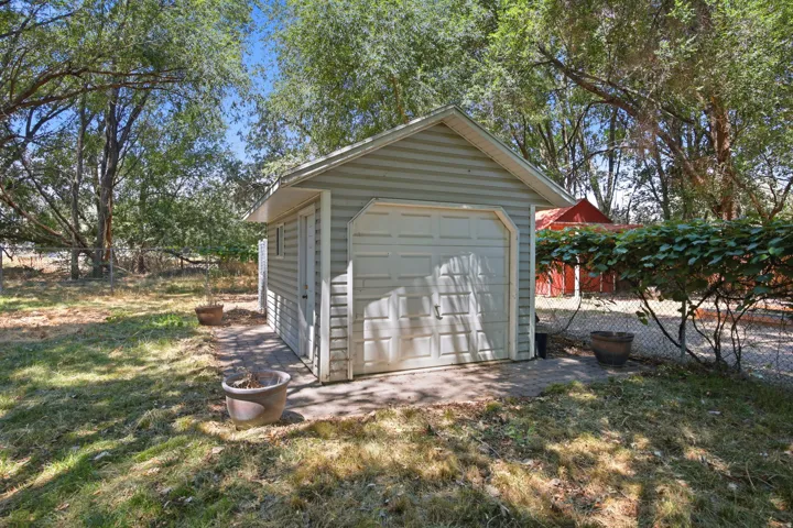 Detached storage shed featuring vinyl siding and a single garage door