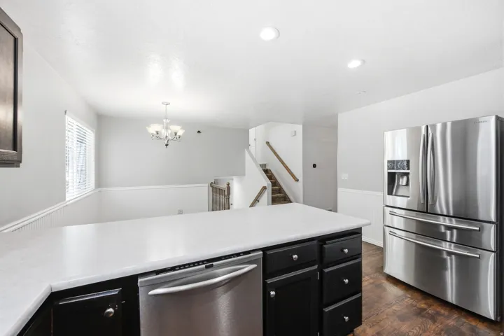 Kitchen island with a light-toned countertop, black cabinetry, and stainless steel dishwasher
