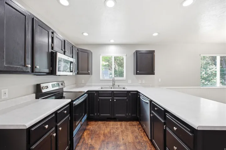 Spacious kitchen featuring dark wood cabinetry, light-toned countertops, and wood-finish flooring