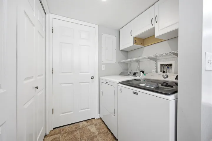 Dedicated laundry area featuring a tile-look floor, white cabinetry, and wire shelving