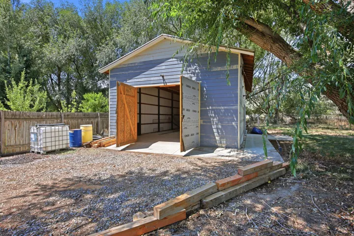 Detached structure featuring blue siding and wooden entry doors