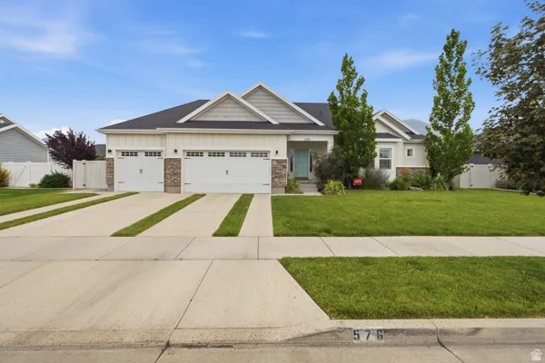 Ranch-style residence featuring a two-car garage with carriage-style doors, stone accents, and board-and-batten siding