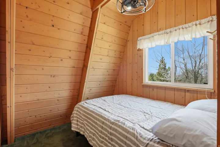Room featuring natural wood plank walls, sloped ceiling, and a large window